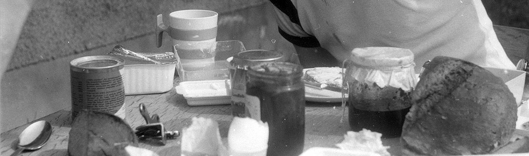 Frühstückstisch mit Honig, Marmelade, Tasse, Brot, Besteck